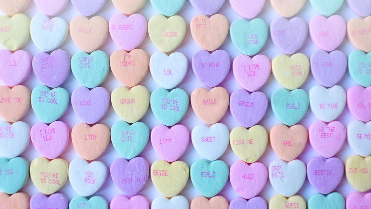 An image with candy hearts laid out on a flat surface. Candy hearts have a variety of messages for Valentine's Day